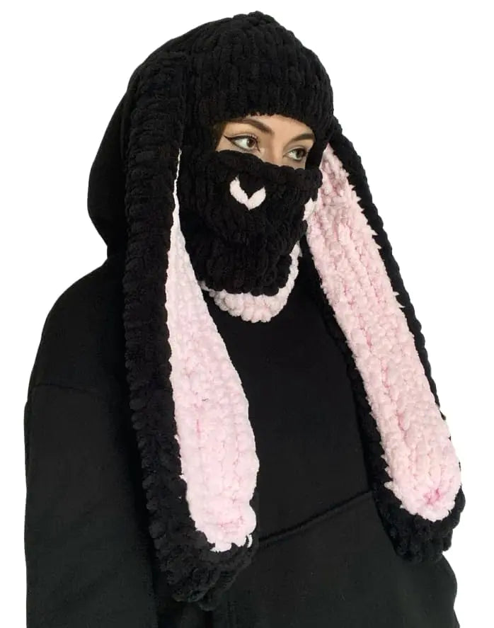 Black knitted bunny hat with pink ears on a white background